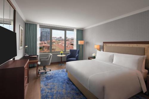 アンカラにあるDivan Ankaraの大きなベッドと大きな窓が備わるホテルルームです。