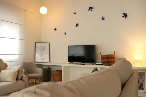 sala de estar con sofá y pájaros en la pared en Casa Anida en Hualle, en Valdáliga