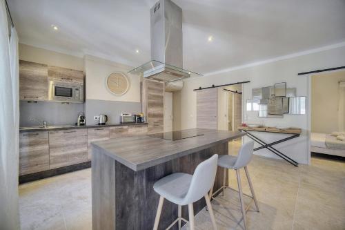 une cuisine avec une grande île et 2 chaises blanches dans l'établissement IMMOGROOM- Apartment 70m2 - Renovated - Wifi - AC - Close to everything, à Cannes
