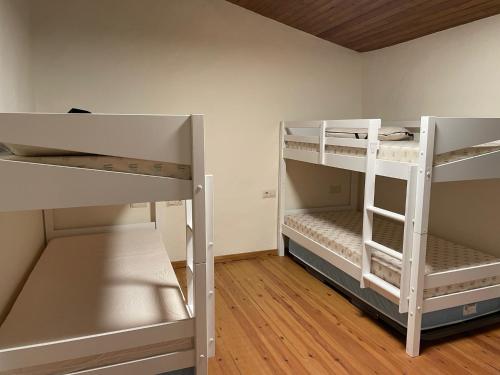 two white bunk beds in a room with wooden floors at Mas Sabaters - L'Era de Sabaters in Tavernoles