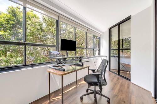 an office with a desk and a chair and windows at Spacious 1 Bedroom Apartment near Newtown in Sydney