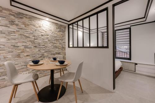 d'une salle à manger avec une table, des chaises et un mur en briques. dans l'établissement Chaleureux plein centre ville et proche du Lac, à Annecy