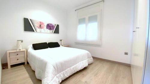 una camera da letto bianca con un letto bianco e una finestra di Rhode 1b a Roses
