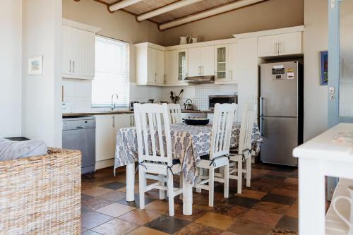 a kitchen with white cabinets and a table and chairs at Twalap in Paternoster