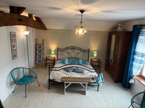 a bedroom with a bed and two chairs and a chandelier at Les Perrières in Saint-Germain-la-Ville