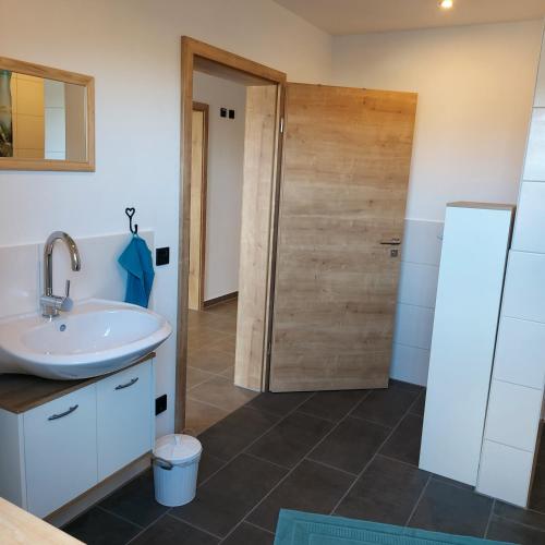 a bathroom with a sink and a wooden door at Ferienwohnung Familie Roth in Rückholz