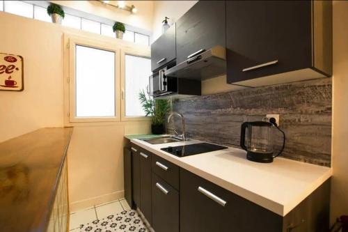 a kitchen with black cabinets and a sink and a window at HSH Traversière Boulogne-Billancourt II Appartement 4P in Boulogne-Billancourt
