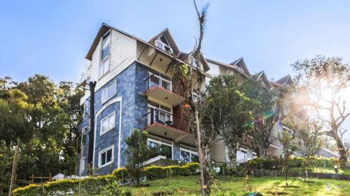 a large blue building with trees in front of it at Shola Crown Resort - Munnar in Chinnakanal