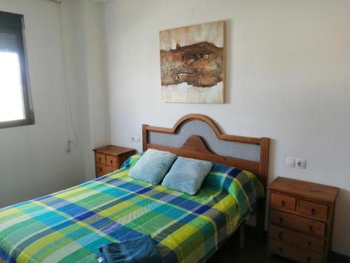 a bedroom with a bed with a colorful plaid blanket at Apartamento Pepe in Alcantarilla