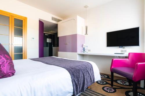 a bedroom with a bed and a tv and a chair at Best Western Plus Hôtel Le Rhénan & Restaurant Chez Claude in Dorlisheim