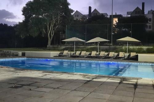 a large swimming pool with chairs and umbrellas at Unit08 on The Eighteenth with inverter at Princes Grant Golf Estate in Blythedale