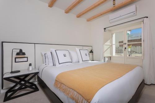 a white bedroom with a large bed and a window at La Fonda Heritage Hotel Luxury, Relais & Châteaux in Marbella