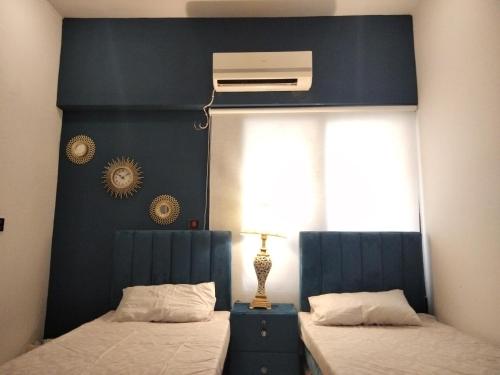 Schlafzimmer mit einem Bett mit blauem Kopfteil in der Unterkunft The Realtors Inn 2 BDR Apartment in Islamabad