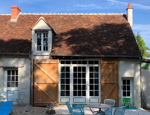 a house with wooden doors and a table and chairs at 'La Ménagerie' in Châteauvieux