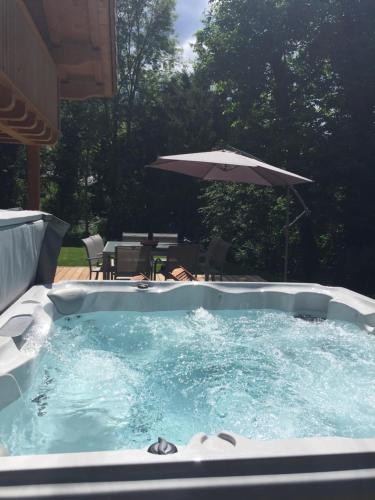 a hot tub with an umbrella in a yard at Chalet Lilalpes SPA in Samoëns