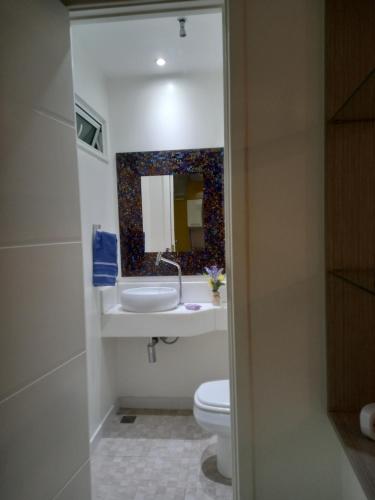 a bathroom with a sink and a toilet and a mirror at Copacabana Beach Modern Apartments in Rio de Janeiro