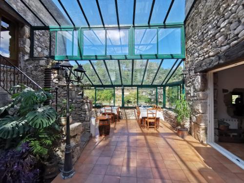 un giardino d'inverno con tetto in vetro, tavoli e sedie. di Le Moulin du Temps -chambres et lounge bar au bord de la rivière a Corbés