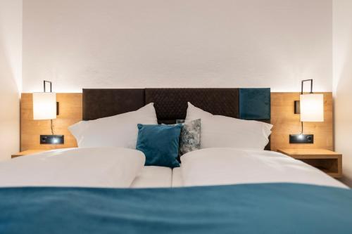 two beds in a bedroom with two lamps on both sides at Hotel Trattnig in Döbriach