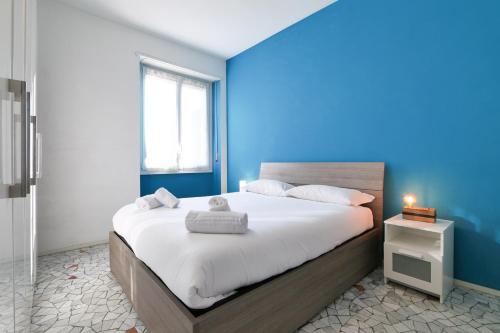- une chambre avec un grand lit et un mur bleu dans l'établissement PrimoPiano - Baldinucci, à Milan