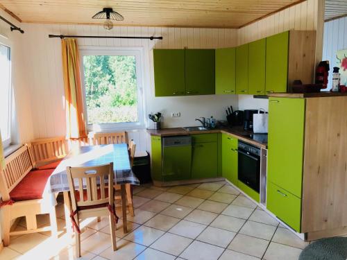 eine Küche mit grünen Schränken und einem Tisch in der Unterkunft Feriendorf Boeker Mühle in Boek