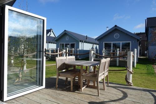 a table and chairs on a deck with a house at Puffin Lodge - Part of the The Bay Filey Holiday Village with pool, gym and direct beach access, pub, restaurant, tennis and meadows walks in Filey