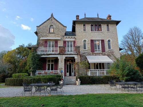 ein großes Haus mit Tischen und Stühlen davor in der Unterkunft Le Pavillon de St Agnan in Hautefort