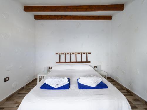 a bedroom with a white bed with blue pillows on it at HomeForGuest Listen to the Ocean in Tufia in Telde