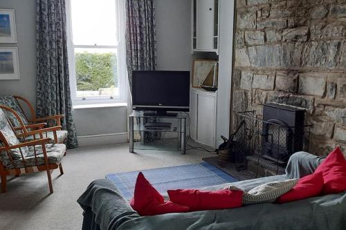 a living room with a couch and a stone fireplace at Arvonia sleeps 7, sea views, dog friendly in New Quay