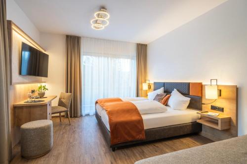 a hotel room with a bed and a desk at Hotel Trattnig in Döbriach