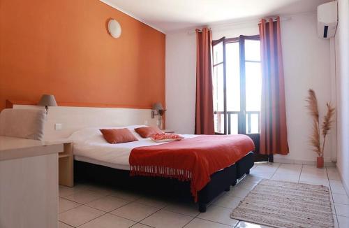 Un dormitorio con una cama con sábanas rojas y una ventana en Hôtel de la jetée en Centuri