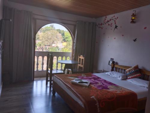 een slaapkamer met een bed en een groot raam bij Magadh ,In Fort Panhala Hotel in Panhāla