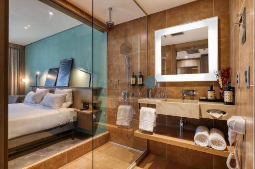 a bedroom with a bed and a sink and a mirror at Novotel BH Savassi in Belo Horizonte