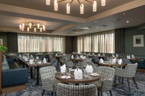 a restaurant with tables and chairs and a chandelier at McWilliam Park Hotel in Claremorris