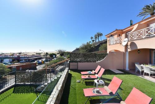 un patio con sedie rosse e tavoli in cima a un edificio di Chalet Santa Ana 2 by VillaGranCanaria a Playa del Ingles