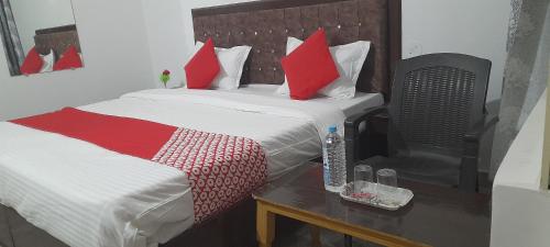 a bedroom with two beds with red pillows and a table at Karma Hostel in Khajurāho