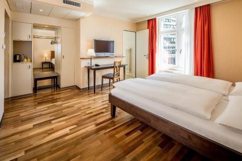 ein Schlafzimmer mit einem großen Bett und einem Schreibtisch in der Unterkunft Hotel Schweizerhof Basel in Basel