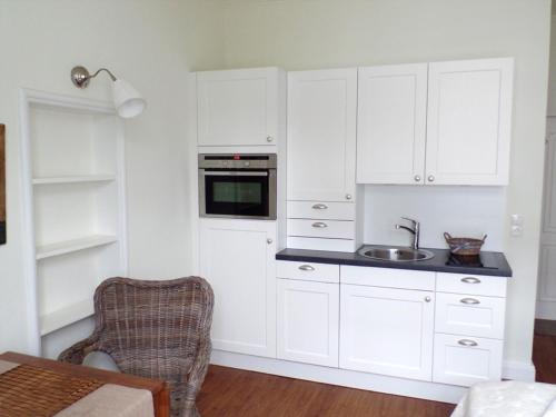 a kitchen with white cabinets and a sink at Villa Silbermöwe in Wyk auf Föhr