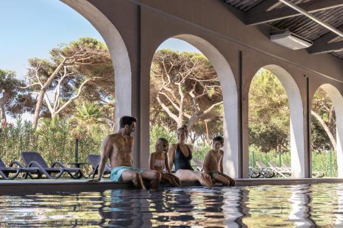 un groupe de personnes assis au bord d'une piscine dans l'établissement Belambra Clubs Presqu'île De Giens - Riviera Beach Club, à Hyères