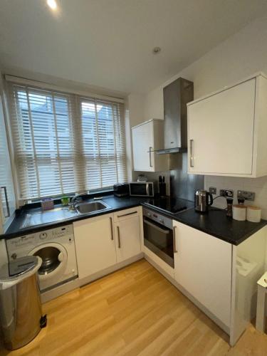 a kitchen with white cabinets and a black counter top at Amazing 2 bedroom apartment in London