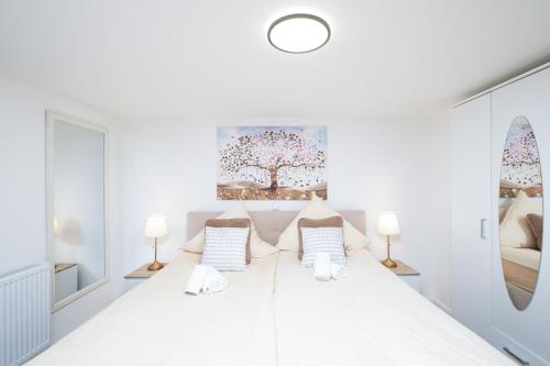 a white bedroom with a large bed with two lamps at Gästehaus "Kleines Stadtidyll" -Zimmer und Apartments by Hotel Holsteiner Hof- in Geesthacht