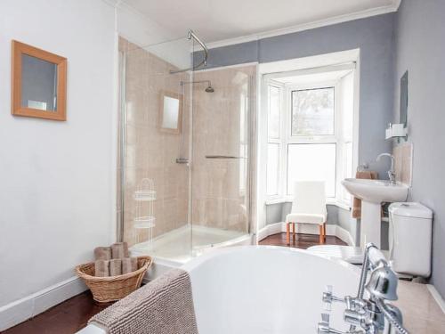 a bathroom with a tub and a sink and a shower at Large House, sleeps 10 with incredible sea views in Ilfracombe