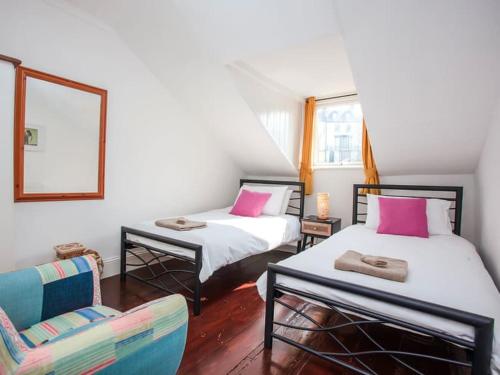 a room with two beds and a chair and a mirror at Large House, sleeps 10 with incredible sea views in Ilfracombe
