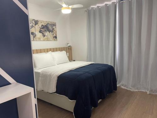 1 dormitorio con 1 cama con manta azul y ventana en Flat completo com piscina, 50m do metrô Brás!, en São Paulo