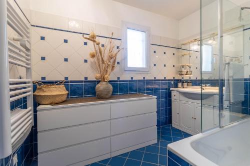 La salle de bains est pourvue de carrelage bleu, d'un lavabo et d'une baignoire. dans l'établissement Villa climatisée, piscine privée chauffée, Fitness proche Cannes, Fréjus, St Raphael, Grasse, à Montauroux