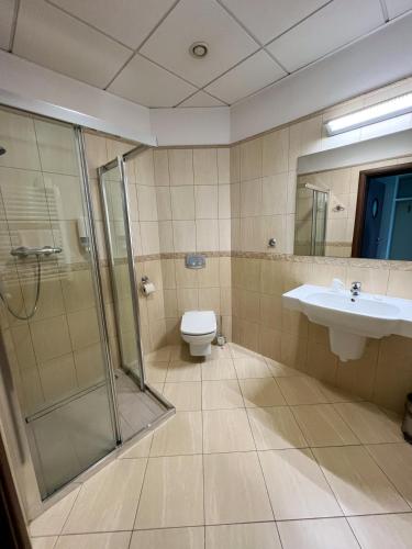 a bathroom with a shower and a toilet and a sink at Hotel Poleski in Krakow