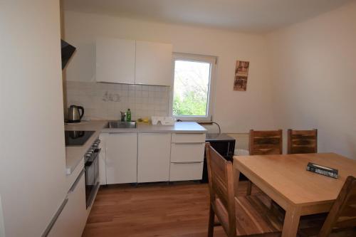 une cuisine avec des placards blancs, une table et une salle à manger dans l'établissement Apartment Maichingen, à Sindelfingen