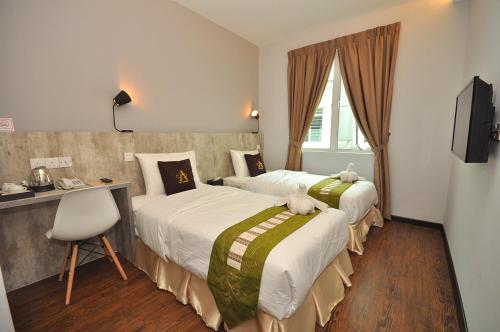 a hotel room with two beds and a desk and a television at Art Cottage Hotel in Ipoh