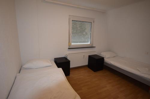 Cette chambre comprend 2 lits et une fenêtre. dans l'établissement Apartment Maichingen, à Sindelfingen