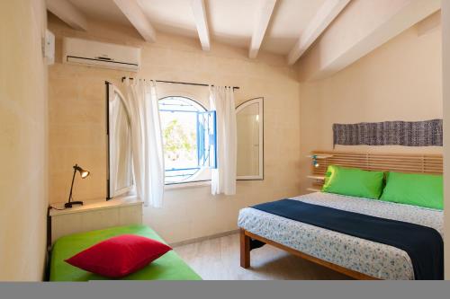 1 dormitorio con almohadas verdes y rojas y ventana en Villa Bruno, en Maruggio