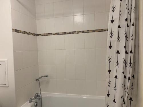 Baño blanco con bañera y cortina de ducha en Ermont paris, en Ermont